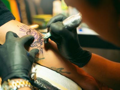 Tattoo artist drawing a tattoo on a person's arm. 